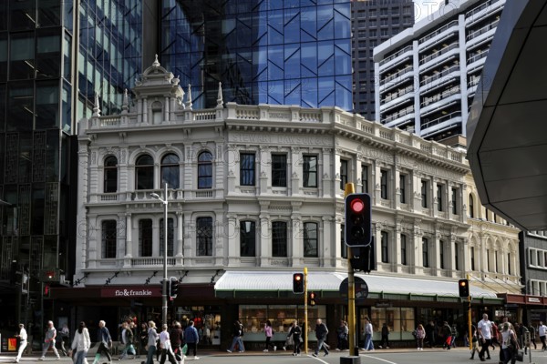 Busy intersection with historic façade contrasting with modern glass buildings on Lambton Quay, Wellington, New Zealand