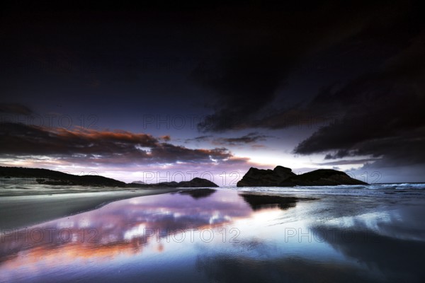 Dramatic sunset on Wharariki Beach with impressive reflection in the water, Wharariki, Tasman, New Zealand