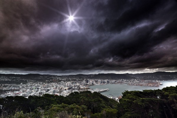 View of Wellington and the ocean from Mount Victoria Lookout under dramatic cloudy sky, Wellington, New Zealand