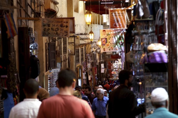 Lively market activity in a narrow, colorful alley with many visitors, Fez, Fez el Bali, Morocco