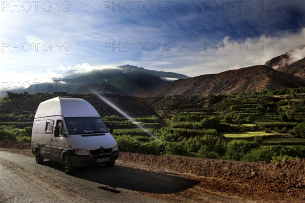 A van on a road with breathtaking views of the green fields of the mountains, Ait Bou Goumez, High Atlas, Morocco
