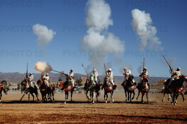 Group of riders fire guns and creates clouds of smoke during a traditional Fantasia ritual, El Kelâa m'Gouna, Morocco