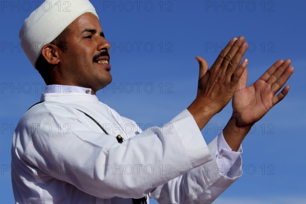 Man in traditional dress claps rhythmically at Berber Festival, Ma El Kelâa M'gouna, Fête des Roses, Berber Dances