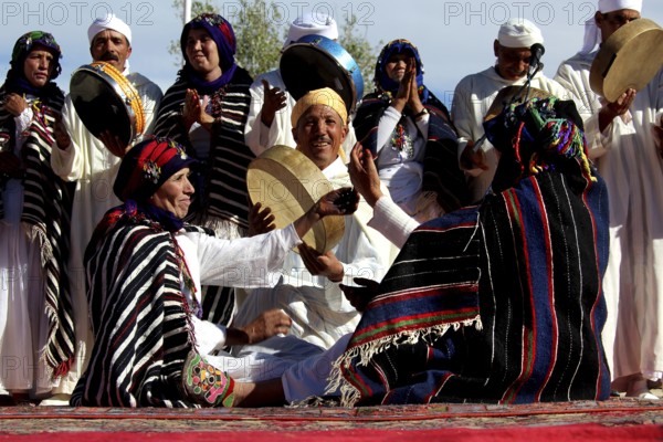 Gathering of men and woman wearing colorful Berber clothes holding drums, El Kelâa m'Gouna