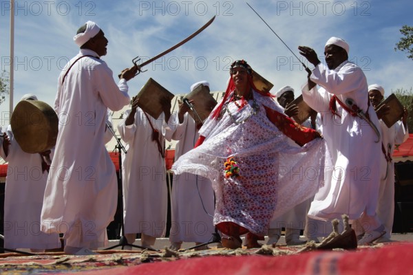 Dancers in white robes perform a sword and drum scene at a Berber festival, El Kelâa m'Gouna