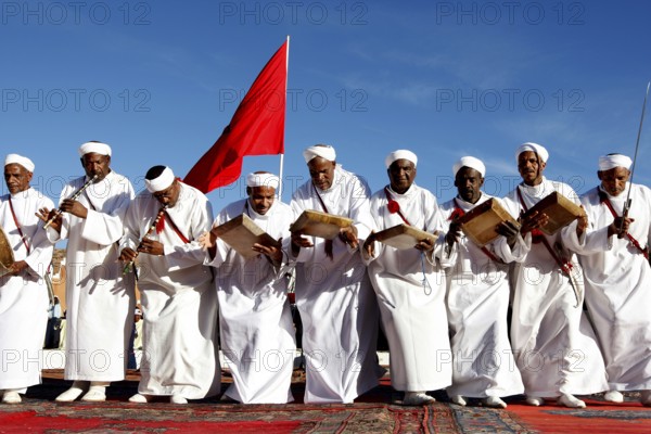 Men in white robes play drums and perform traditional Berber dance, El Kelâa m'Gouna