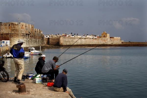 View of fishermen at the harbor with the Cité Portugaise in the background, El Jadida, Doukkala-Abda region, Morocco