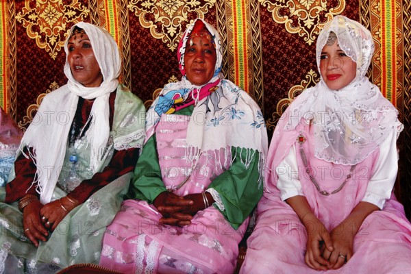 Three woman in traditional dress sit in a tent during the rose festival in El Kelâa m'Gouna, El Kelâa m'Gouna, null, Morocco