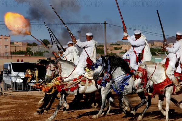 Riding group shoots in sync with rifles and creates fire and smoke in the midst of a traditional backdrop, El Kelâa m'Gouna, Morocco
