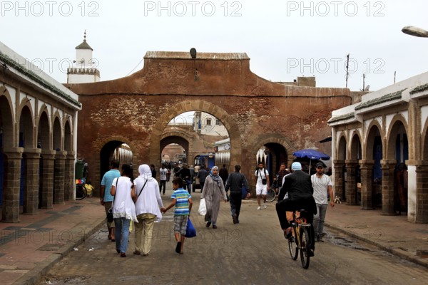 People walk through a historic stone gate in the souk of Essaouira, Essaouira, Morocco