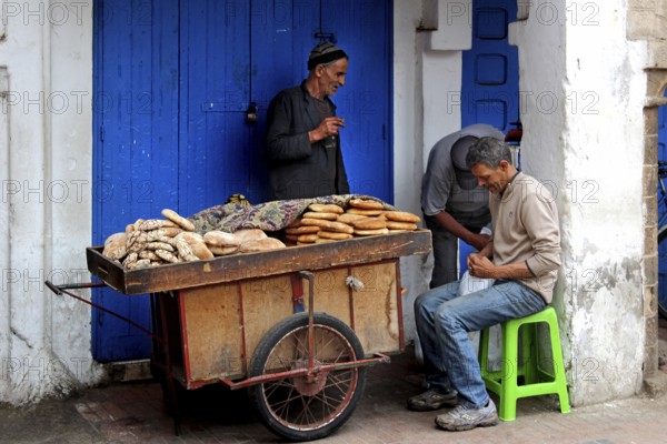 Vendor offers bread from a handcart in Essaouira souk, Essaouira, Morocco