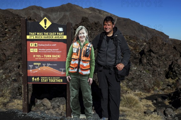 Rangers and hikers next to a warning sign at Tongariro Alpine Crossing, Tongariro National Park, North Island, New Zealand