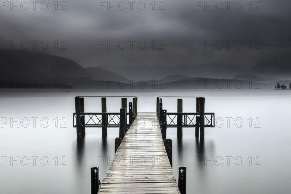 Wooden walkway leads into foggy Lake Te Anau, surrounded by mystical atmosphere, Te Anau, Southland, New Zealand