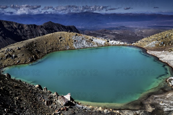 The emerald green lake is nestled in a barren volcanic landscape, Tongariro National Park, New Zealand