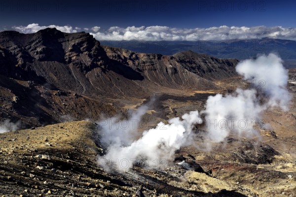 Solfatars escape steaming from the rocky landscape with views of the Emerald Lakes, Tongariro National Park, New Zealand