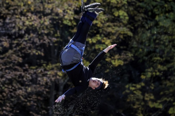 Single jumper doing a somersault in the air in front of an autumn tree backdrop, Queenstown, Otago, New Zealand