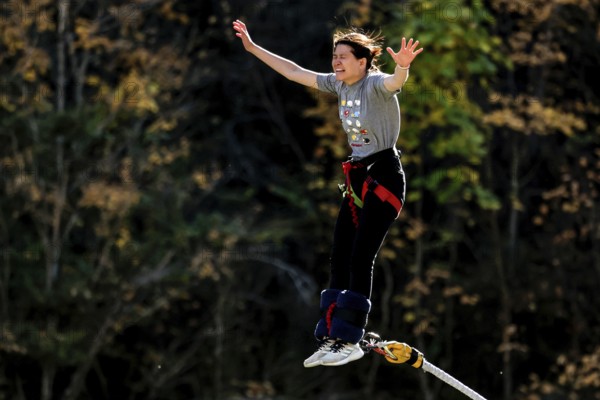 Female bungee jumping off Kawarau Bridge in the midst of autumn forest scenery, Queenstown, Otago, New Zealand