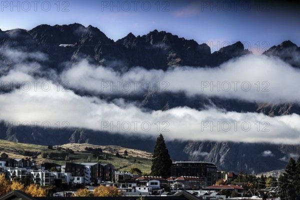 Impressive mountain landscape with clouds over the city of Queenstown, Queenstown, New Zealand
