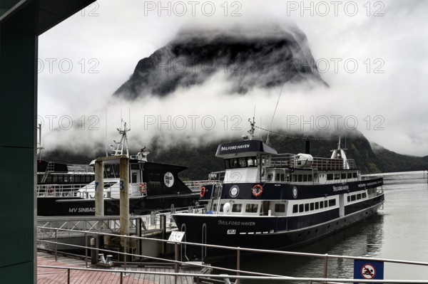 Cruise ship in Milford Sound terminal surrounded by misty mountains, Milford Sound, New Zealand