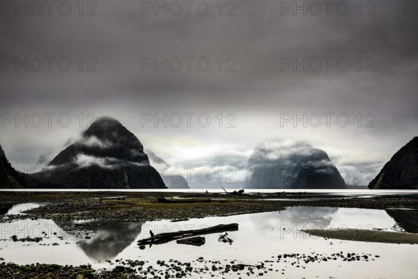 Mirroring water surfaces and mist-covered mountains in Milford Sound create a calm, mystical atmosphere, zero