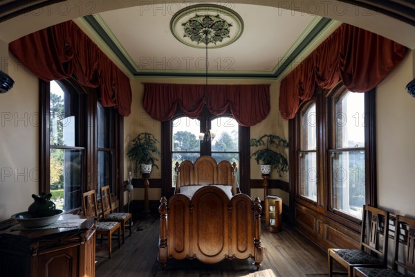 Comfortable bedroom with fine furnishings, large windows and red curtains, Larnach Castle, Otago Peninsula, New Zealand