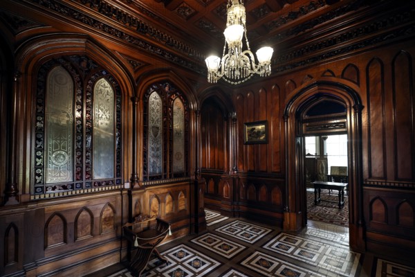 Antique foyer with intricate wood ornaments and a chandelier, Larnach Castle, Otago Peninsula, New Zealand