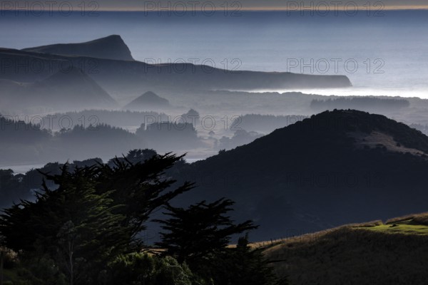 Blurred hills in morning fog along Highcliff Road, Otago Peninsula, New Zealand
