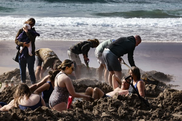 People digging in sand on a beach near the sea, Hot Water Beach, Coromandel Peninsula, New Zealand