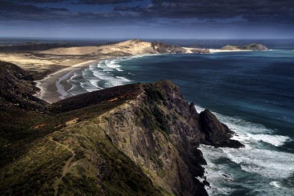 Coastline with steep cliffs and surf waves under a cloudy sky, Cape Reinga, Northland, New Zealand