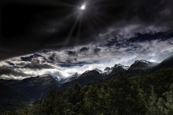 Dramatic snow-covered mountain landscape under a cloudy sky, Milford Road, New Zealand