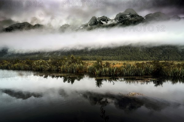 Mountain landscape with dramatic sky is clearly reflected in the calm lake, Mirror Lakes, New Zealand