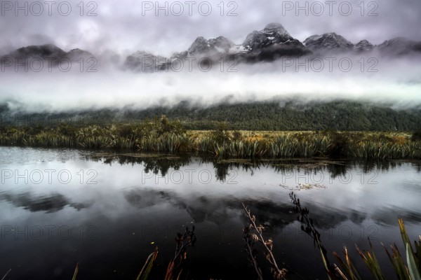 Reflection of snow-capped mountains in calm waters of Mirror Lakes, Milford Road, New Zealand