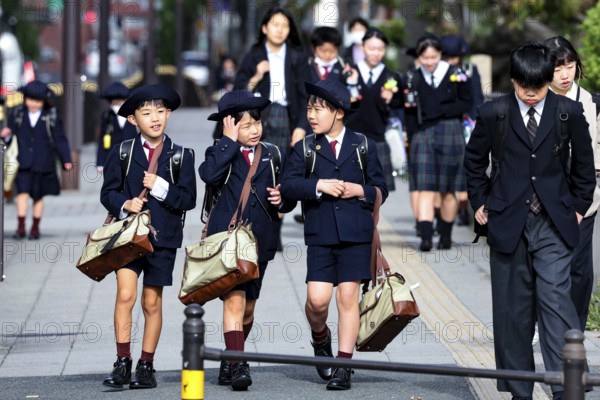 Group of schoolchildren wearing uniforms on a busy sidewalk in Osaka, Osaka, Japan