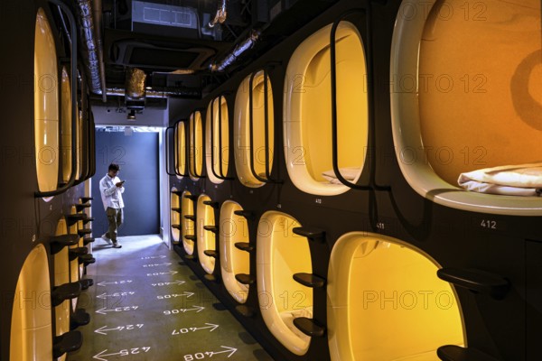 Aisle of a modern capsule hotel with illuminated sleeping capsules, Tokyo, zero, Japan