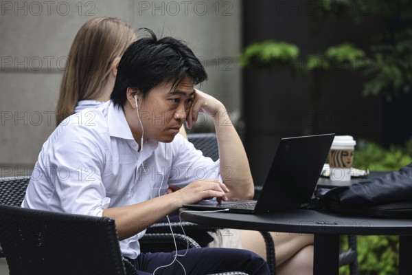 A salariman concentrates on a laptop outdoors, Tokyo, Hamamatsucho, Japan