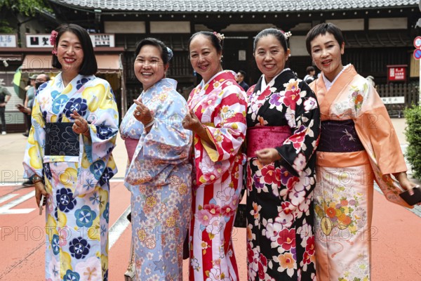 Group of woman wearing colorful kimonos against a traditional backdrop in Tokyo, Tokyo, Asakusa, Japan