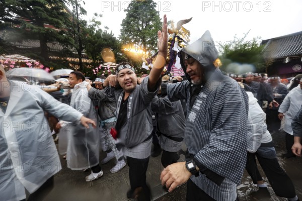 Participants wearing raincoats celebrate on Sanja Matsuri despite the rain, Tokyo, Asakusa, Japan