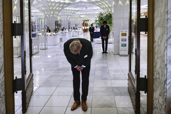 Employee greets customers with traditional bow at Mitsukoshi Department Store, Tokyo, Japan