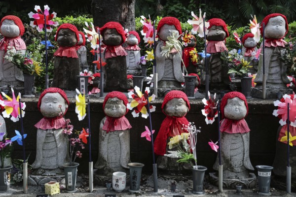 Many jizo statues with red cloths and wind turbines at Zojo-ji Shrine in Minato, Tokyo, Tokyo, Japan