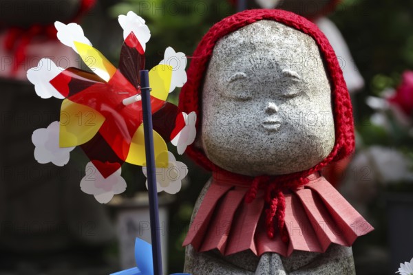 Jizo statue with red cloth and wind turbine at Zojo-ji shrine in Minato, Tokyo, Tokyo, Japan