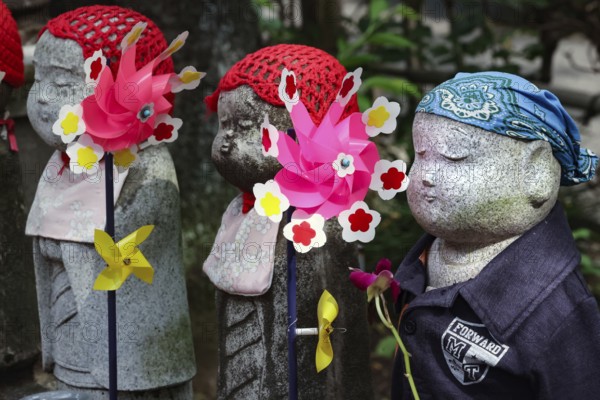 Row of jizo statues with colorful wind turbines at Zojo-ji Shrine in Minato, Tokyo, Tokyo, Japan