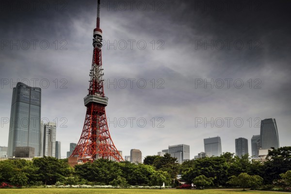 Tokyo Tower stands out on the horizon surrounded by green spaces and clouds, Tokyo, Japan