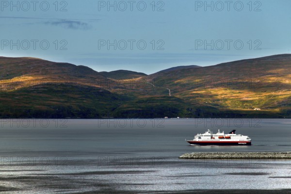 Hurtigruten ship off the wooded hills of Hammerfest on calm water, Hammerfest, Finnmark, Norway