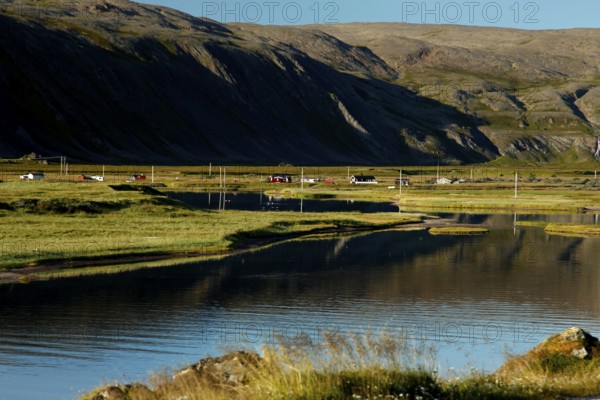 Coastal road and landscape near Hamningberg, reflecting water and quiet hills