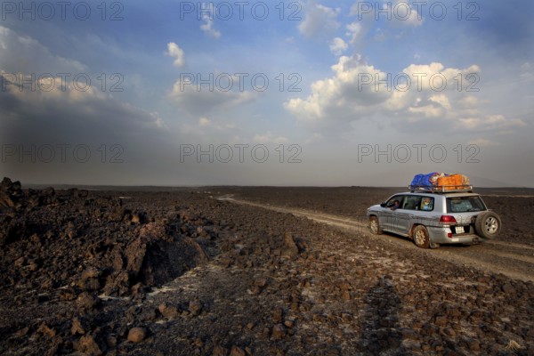 Landcruiser drives through the lava desert under a dramatic sky, zero