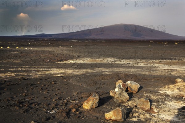 Wide view of the dry, rocky landscape of a lava desert with background mountain
