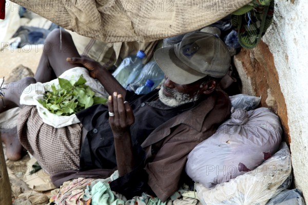 Man relaxes in Harar and consumes khat in improvised shelter, Harar, Oromia, Ethiopia