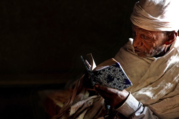 Priest reading in low light at Debre Berhan Selassie church, zero