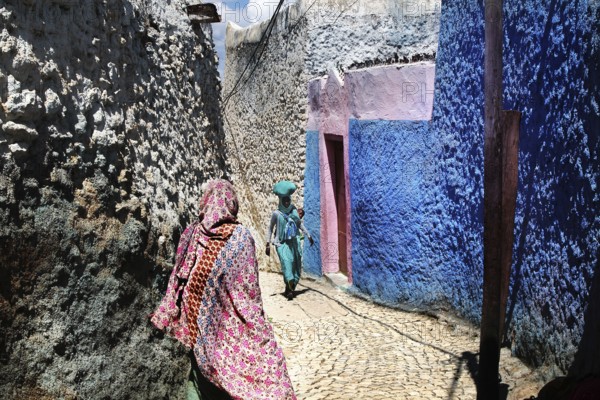 Narrow alley in Harar with eye-catching colors and passers-by, Harar, Ethiopia
