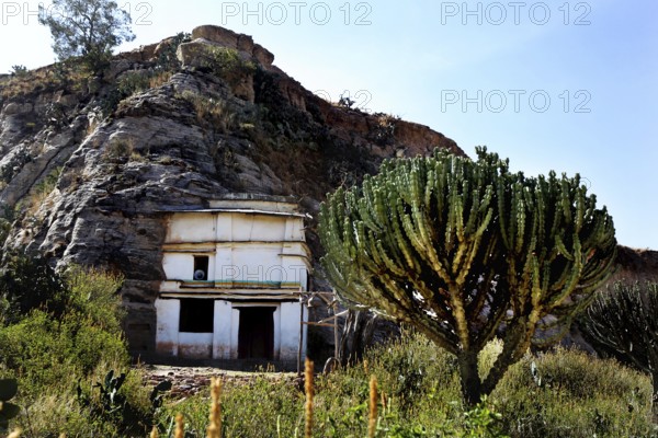 Entrance to Debre Mariam Krokor rock church in front of a steep rock face in natural surroundings, zero